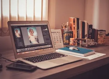 A laptop on a wooden desk showing a photo story being edited.