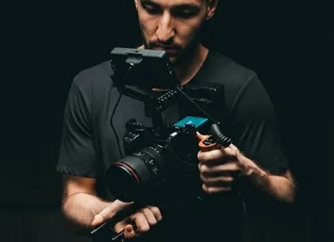 A photographer holding a camera mounted on a handheld gimbal.